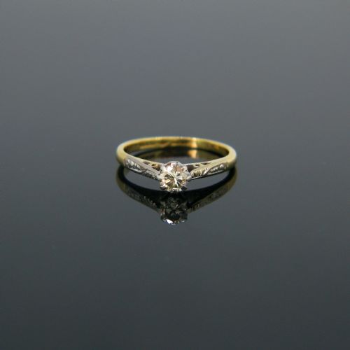 fig 1. An 18kt yellow gold and platinum solitaire ring set with a central diamond in a carved mount.