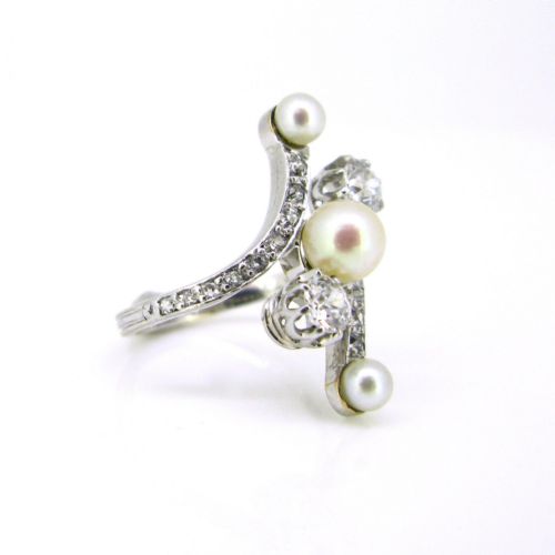 fig 1. An Edwardian platinum and white gold crossover ring set with central natural pearls and round diamonds along curved shoulders.
