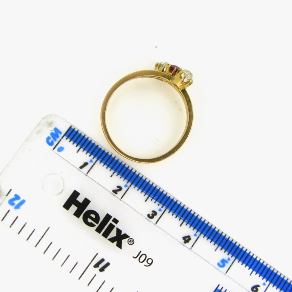 An antique yellow gold Victorian ring featuring a triple wire shank set with a central red ruby flanked by two bright diamonds. View VII