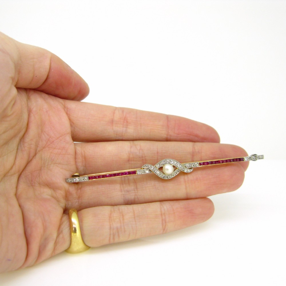An Edwardian platinum and gold bar brooch set with calibre-cut red rubies, diamonds, and a central pearl. View III