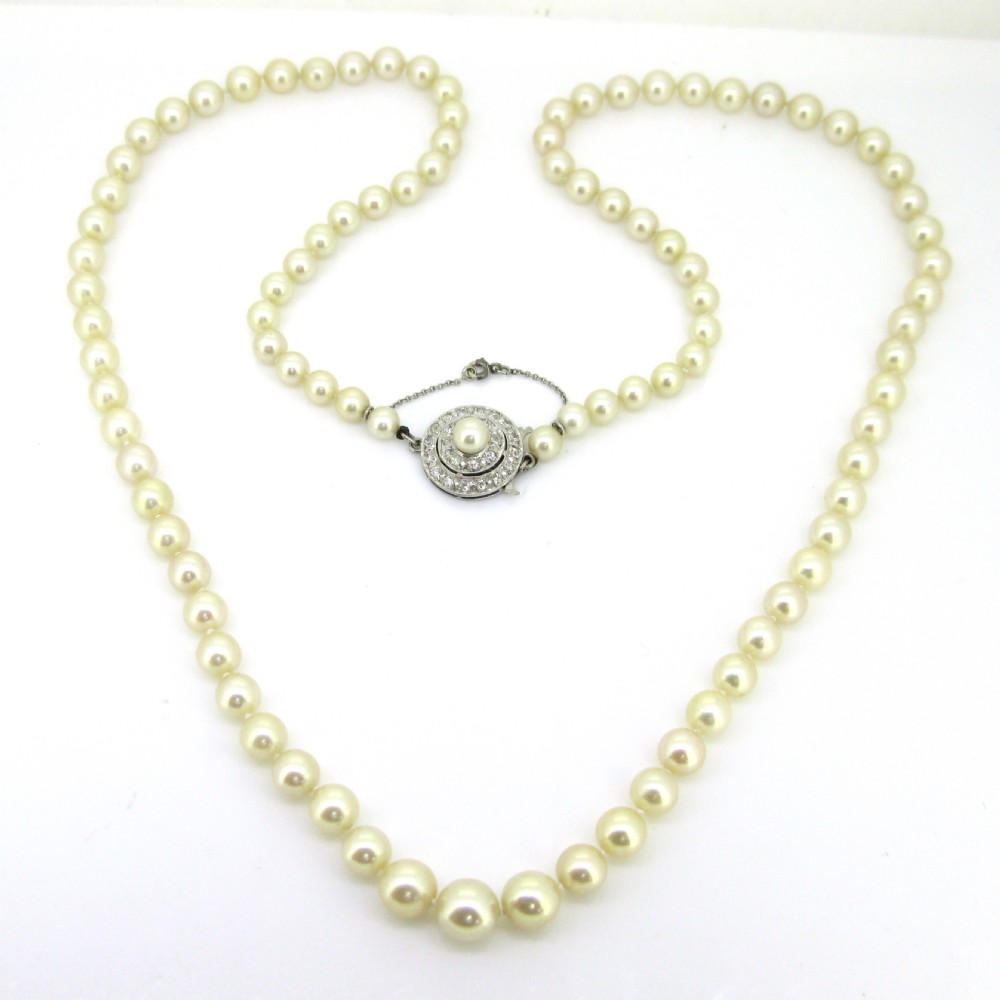 A single strand of cream cultured pearls featuring a circular diamond-set 18ct white gold clasp with a safety chain. View II