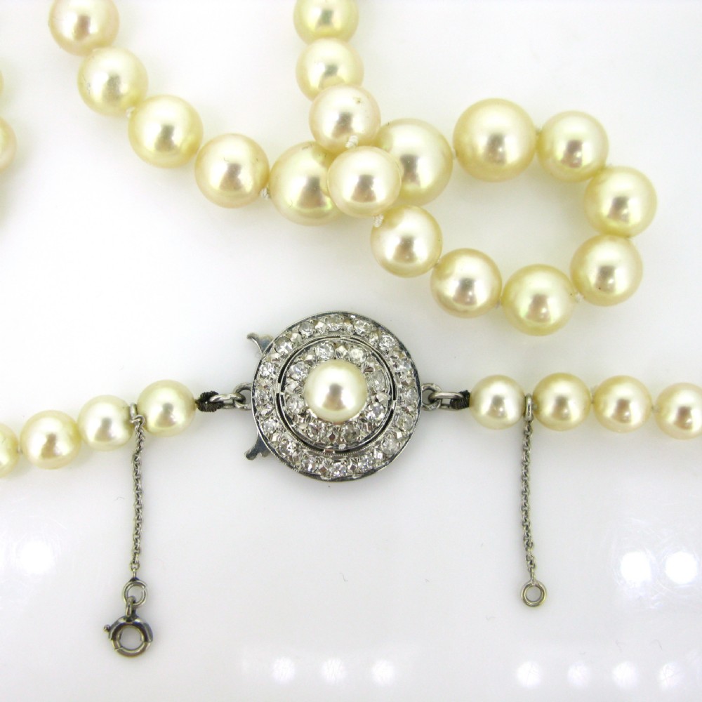 A single strand of cream cultured pearls featuring a circular diamond-set 18ct white gold clasp with a safety chain. View IV