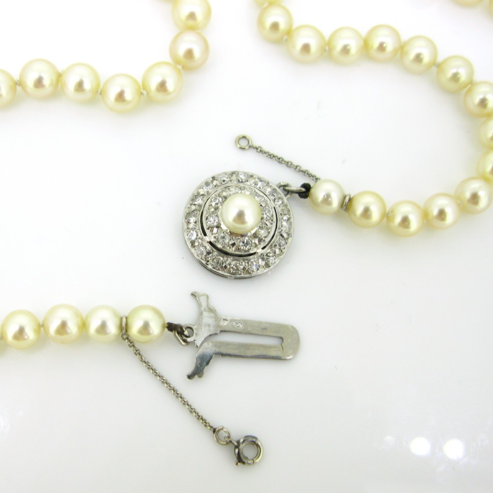 A single strand of cream cultured pearls featuring a circular diamond-set 18ct white gold clasp with a safety chain. View V