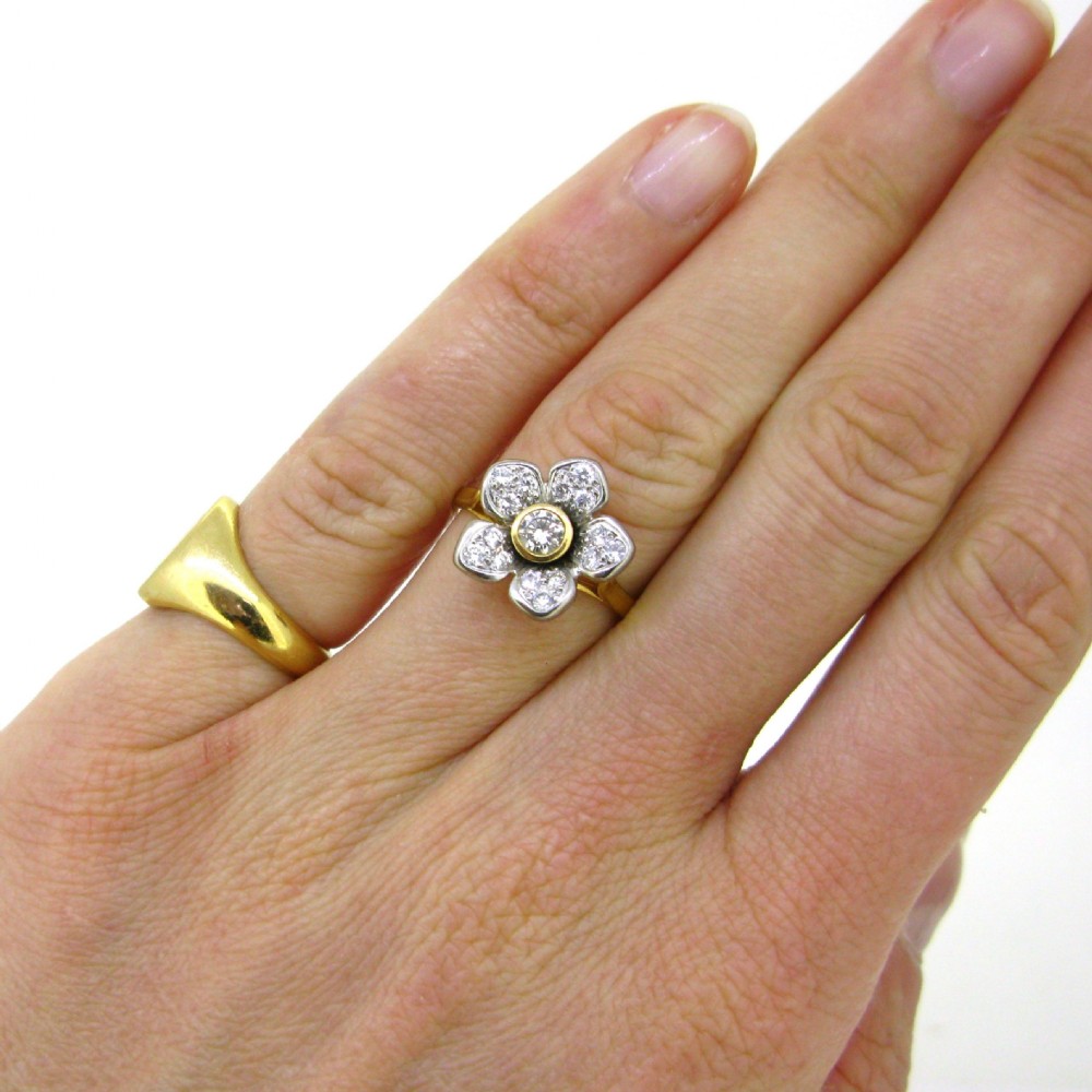 A vintage 18-carat yellow and white gold ring featuring a central diamond surrounded by five diamond-set petals forming a floral cluster. View VII