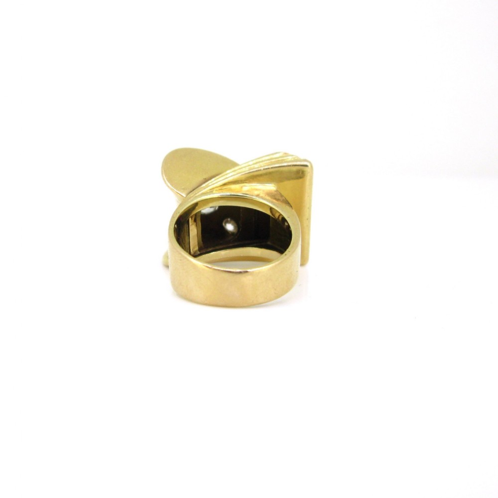 An 18ct yellow gold 1940s Retro Tank ring featuring a sculptural scroll motif set with diamonds and channel-set red rubies. View V