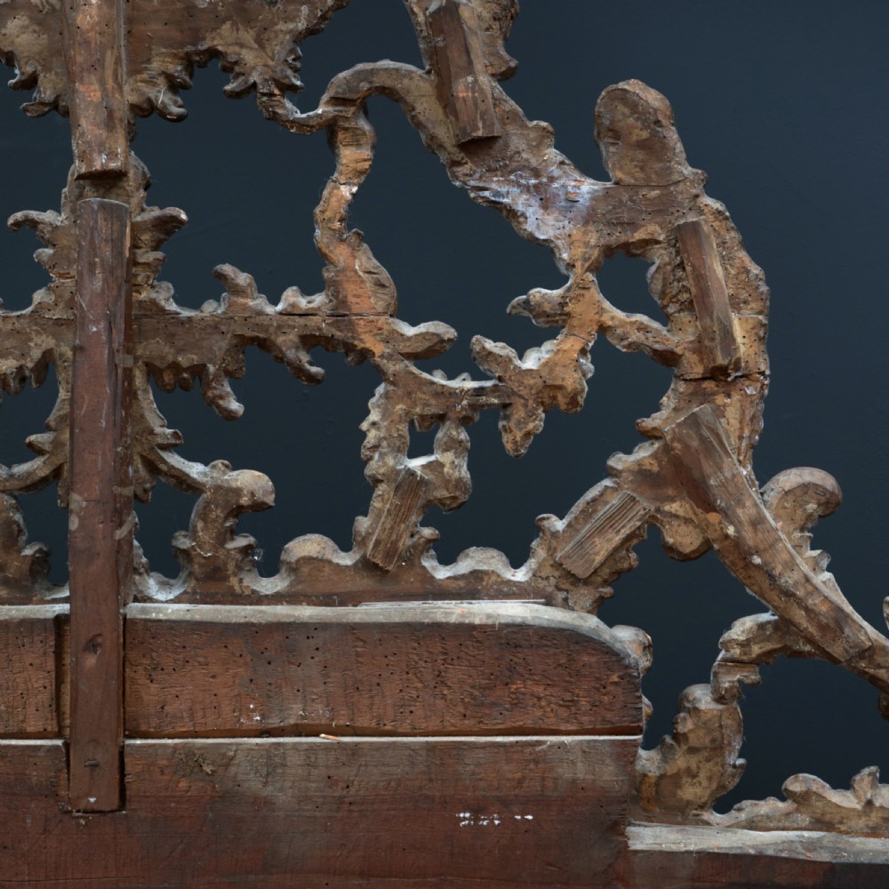 An 18th-century silvered Rococo overmantel mirror featuring an elaborately carved crest with C-scrolls and a tripartite mirror plate with visible foxing. View XVIII