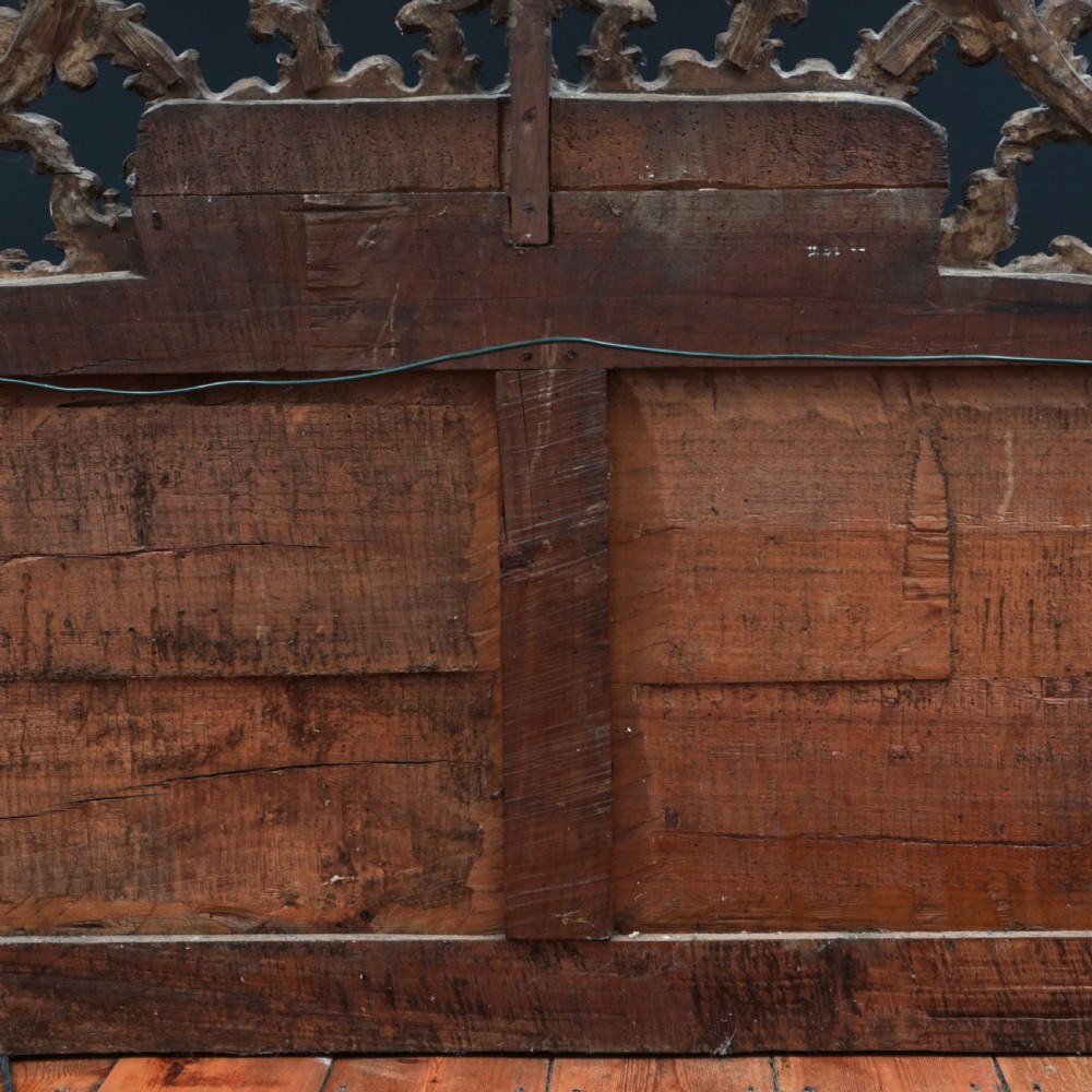 An 18th-century silvered Rococo overmantel mirror featuring an elaborately carved crest with C-scrolls and a tripartite mirror plate with visible foxing. View XXI