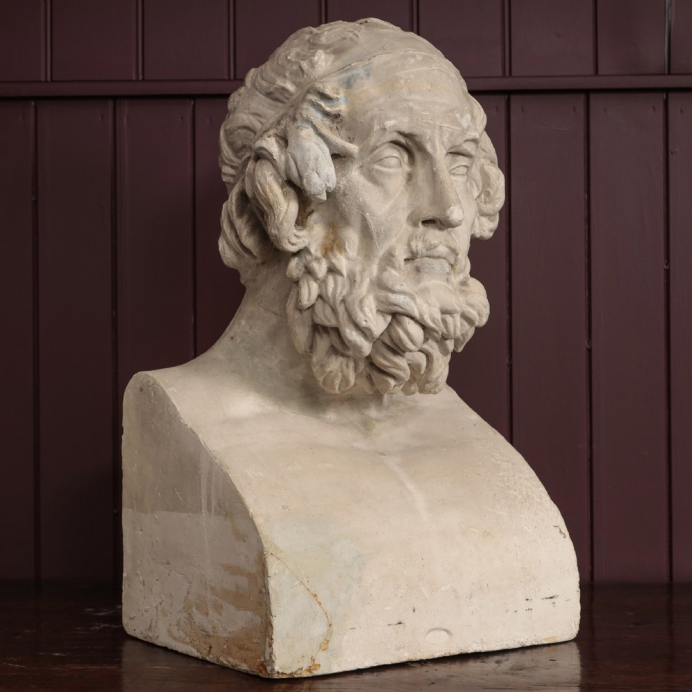 An off-white plaster bust depicting the classical Greek poet Homer with a detailed curly beard and headband, set on a flat square base. View IV