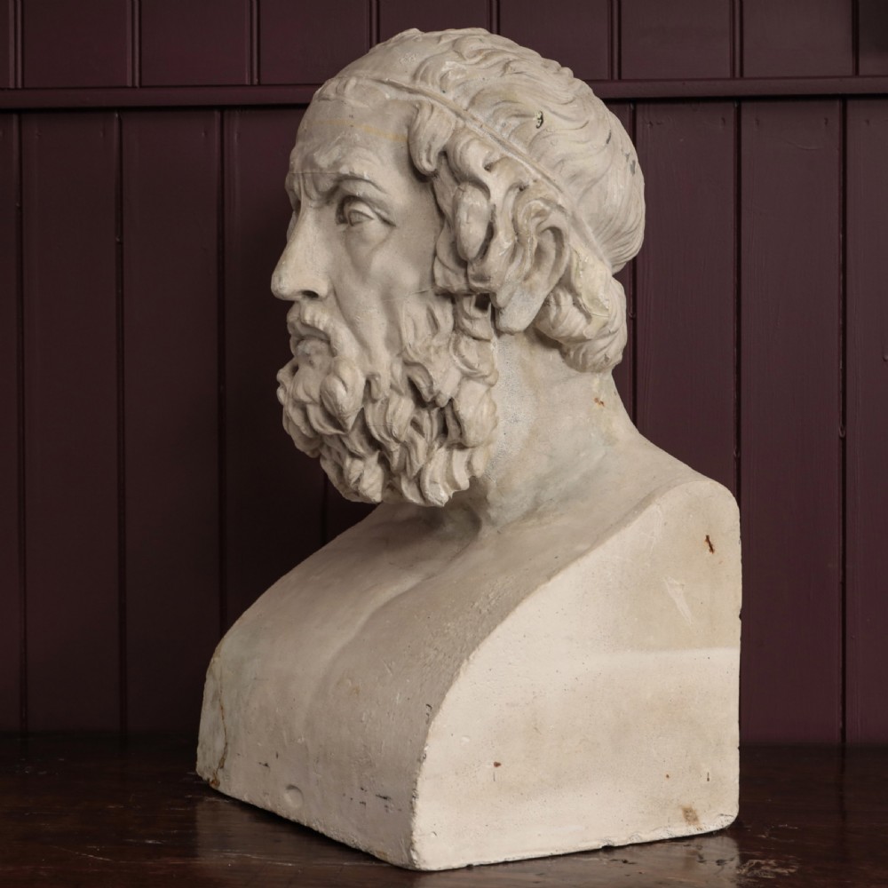 An off-white plaster bust depicting the classical Greek poet Homer with a detailed curly beard and headband, set on a flat square base. View VIII