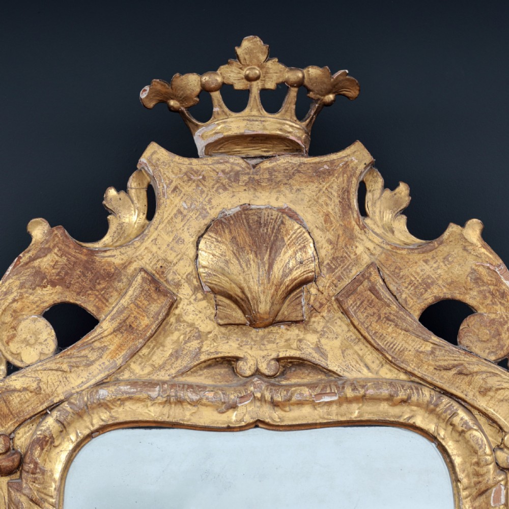 A tall George I period giltwood wall mirror featuring an ornate carved crown cresting, shell motif, and a two-section mirror plate. View III