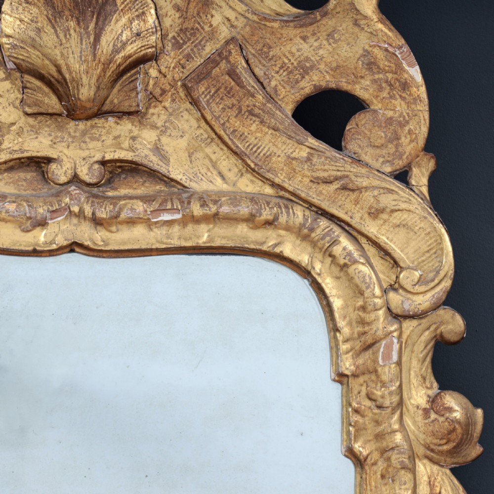 A tall George I period giltwood wall mirror featuring an ornate carved crown cresting, shell motif, and a two-section mirror plate. View IV