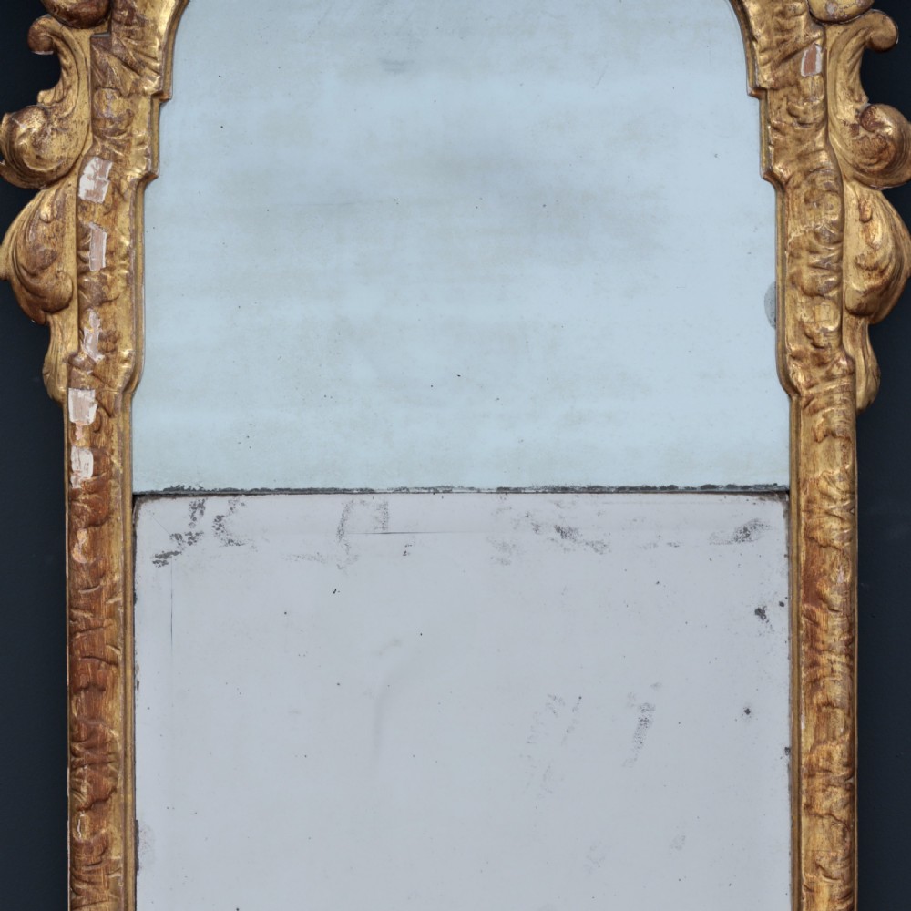 A tall George I period giltwood wall mirror featuring an ornate carved crown cresting, shell motif, and a two-section mirror plate. View VII