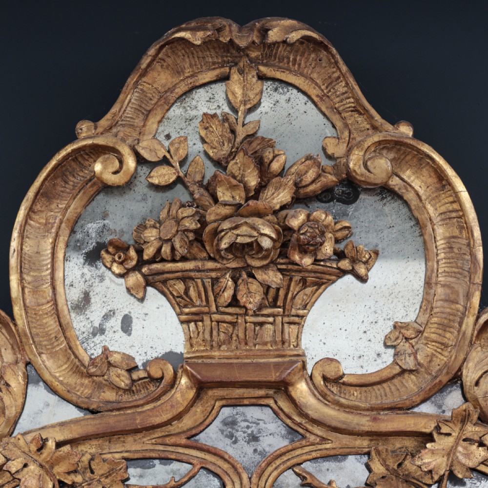 An ornate Louis XV style gilded mirror featuring a carved timber frame with vine motifs and a flower basket crest. View III