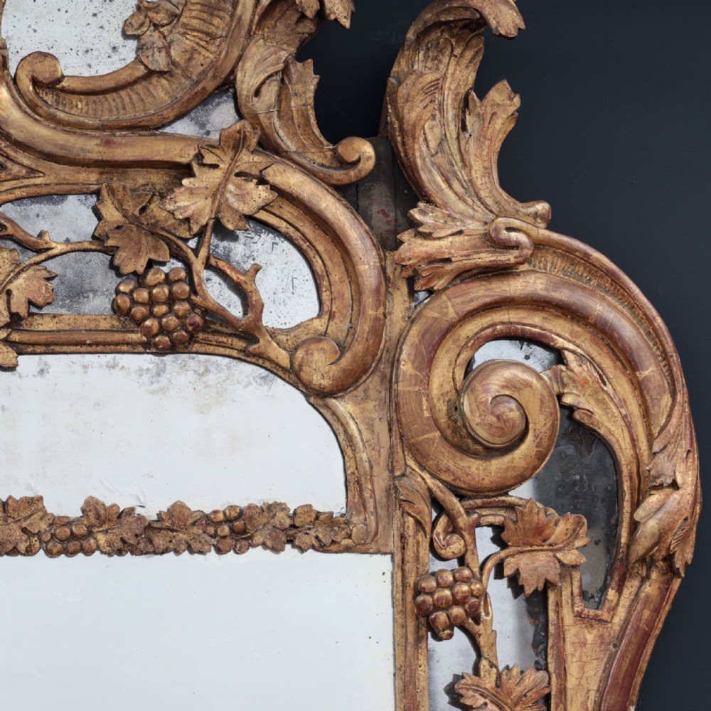 An ornate Louis XV style gilded mirror featuring a carved timber frame with vine motifs and a flower basket crest. View IV