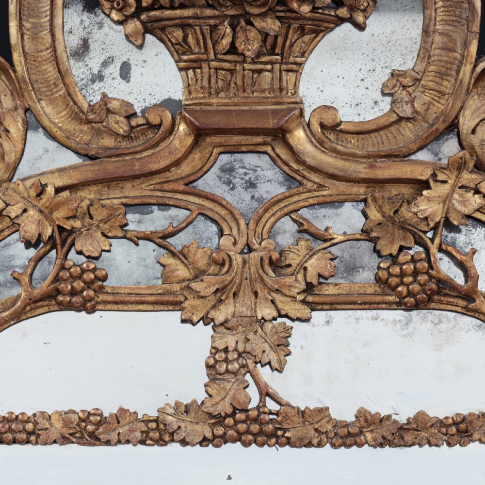 An ornate Louis XV style gilded mirror featuring a carved timber frame with vine motifs and a flower basket crest. View V