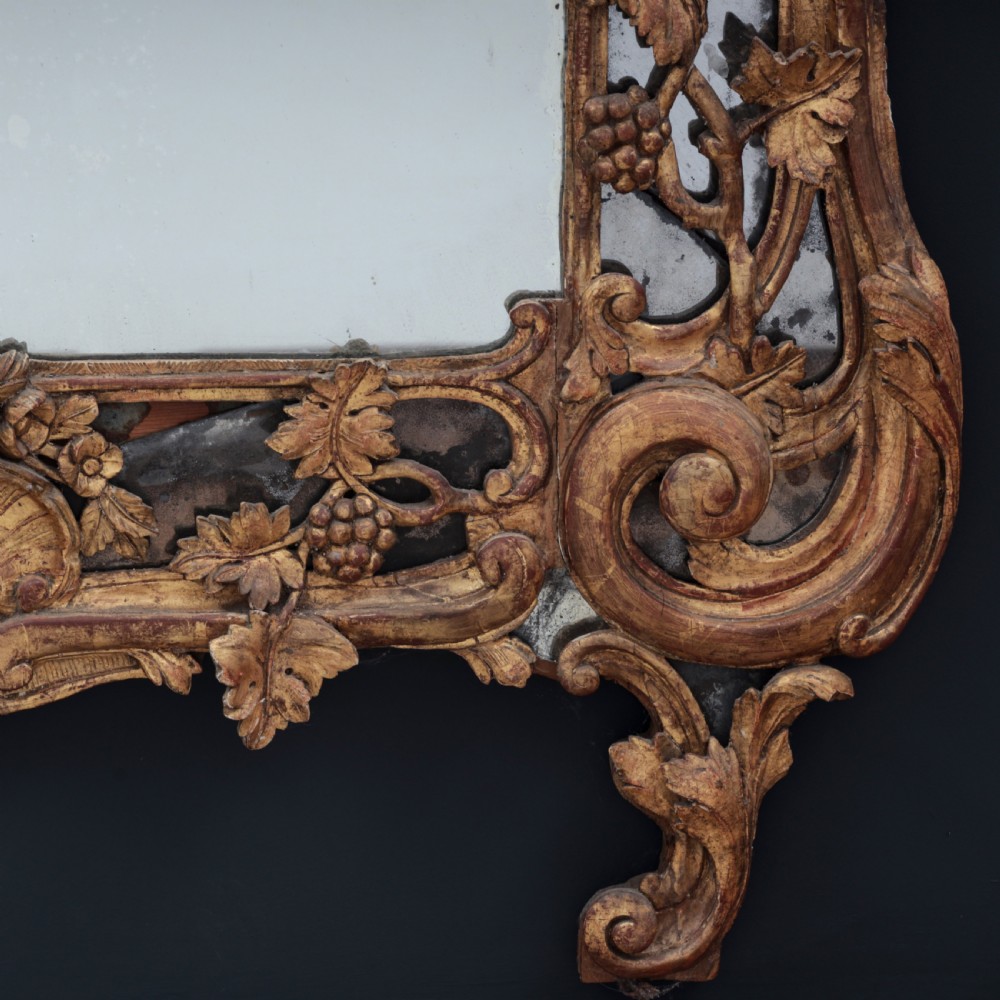 An ornate Louis XV style gilded mirror featuring a carved timber frame with vine motifs and a flower basket crest. View VI