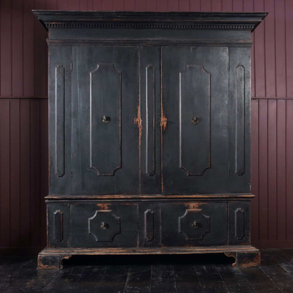 An 18th-century Tuscan cabinet featuring a distressed black painted finish, moulded cornice, panelled double doors, and lower drawers on bracket feet.