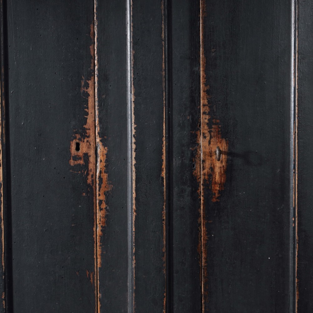 An 18th-century Tuscan cabinet featuring a distressed black painted finish, moulded cornice, panelled double doors, and lower drawers on bracket feet. View III