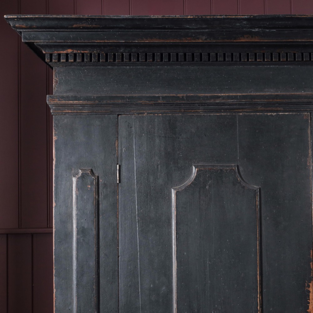 An 18th-century Tuscan cabinet featuring a distressed black painted finish, moulded cornice, panelled double doors, and lower drawers on bracket feet. View V
