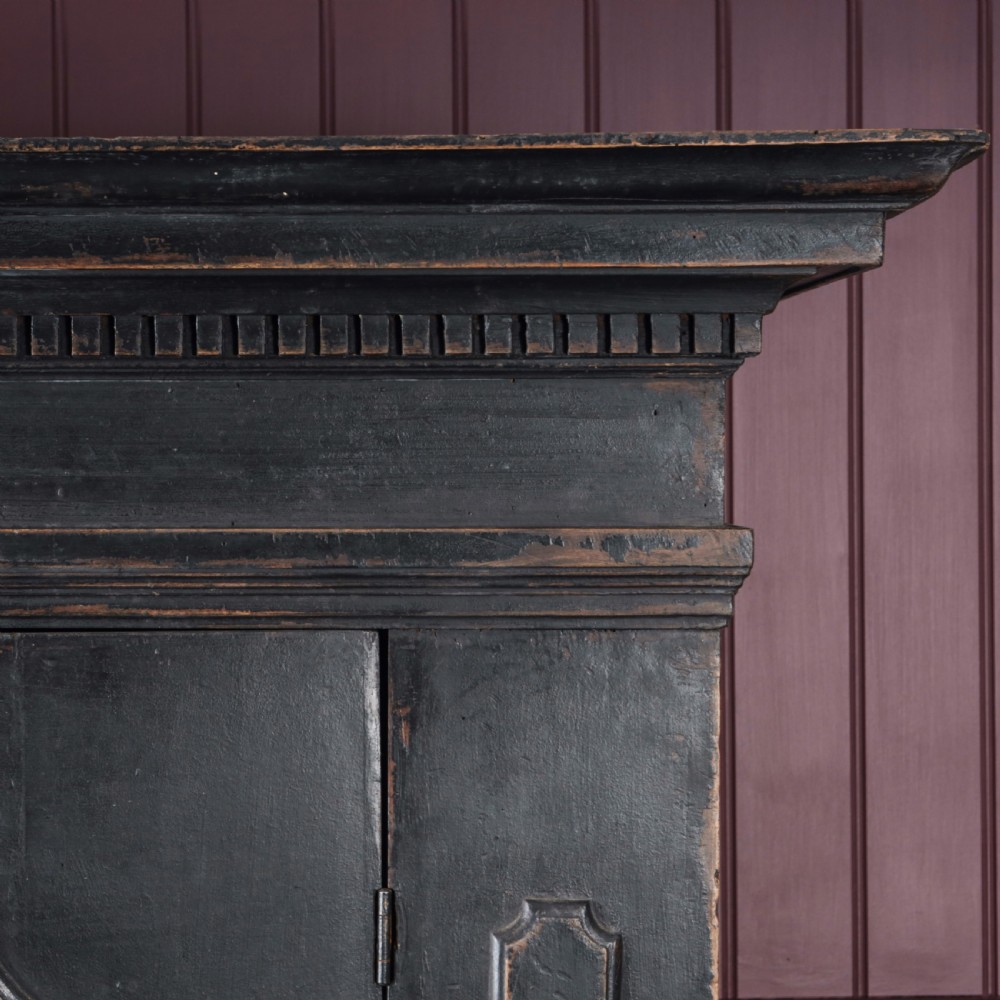 An 18th-century Tuscan cabinet featuring a distressed black painted finish, moulded cornice, panelled double doors, and lower drawers on bracket feet. View XI
