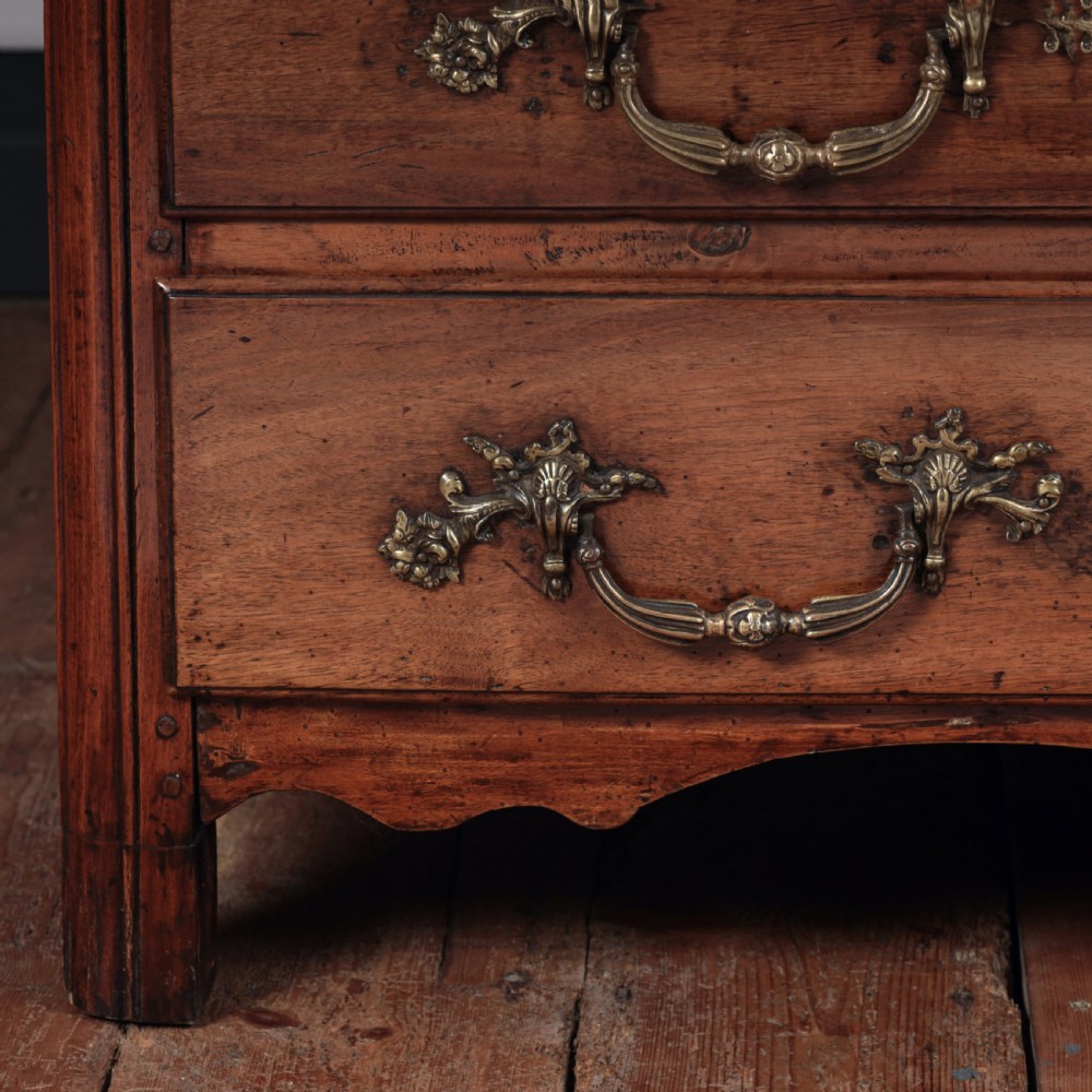 A French Louis XV style warm walnut commode featuring four drawer levels with ornate brass scroll handles and keyhole escutcheons. View VI