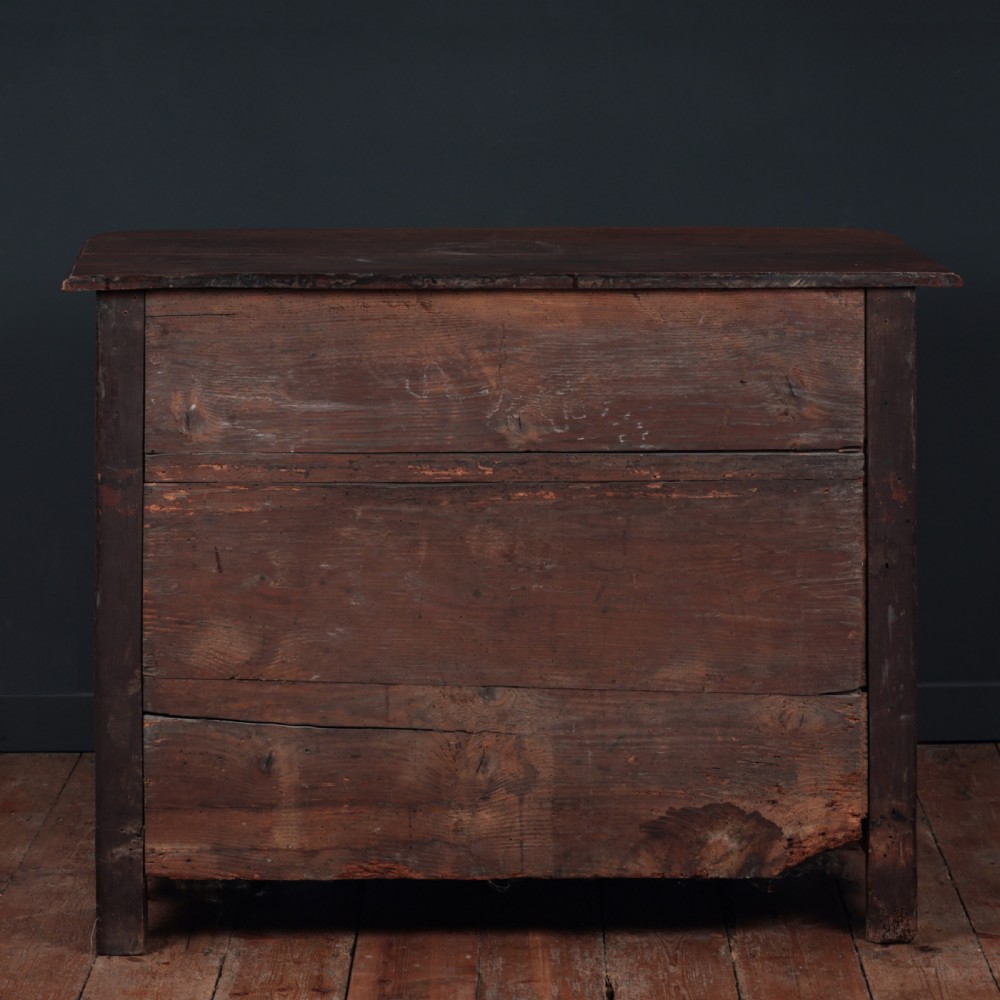 A French Louis XV style warm walnut commode featuring four drawer levels with ornate brass scroll handles and keyhole escutcheons. View X