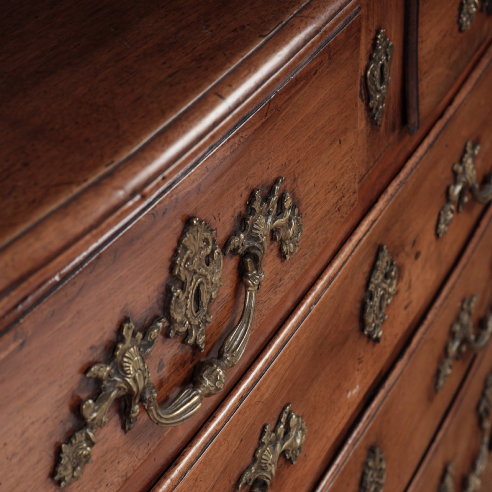 A French Louis XV style warm walnut commode featuring four drawer levels with ornate brass scroll handles and keyhole escutcheons. View XIII