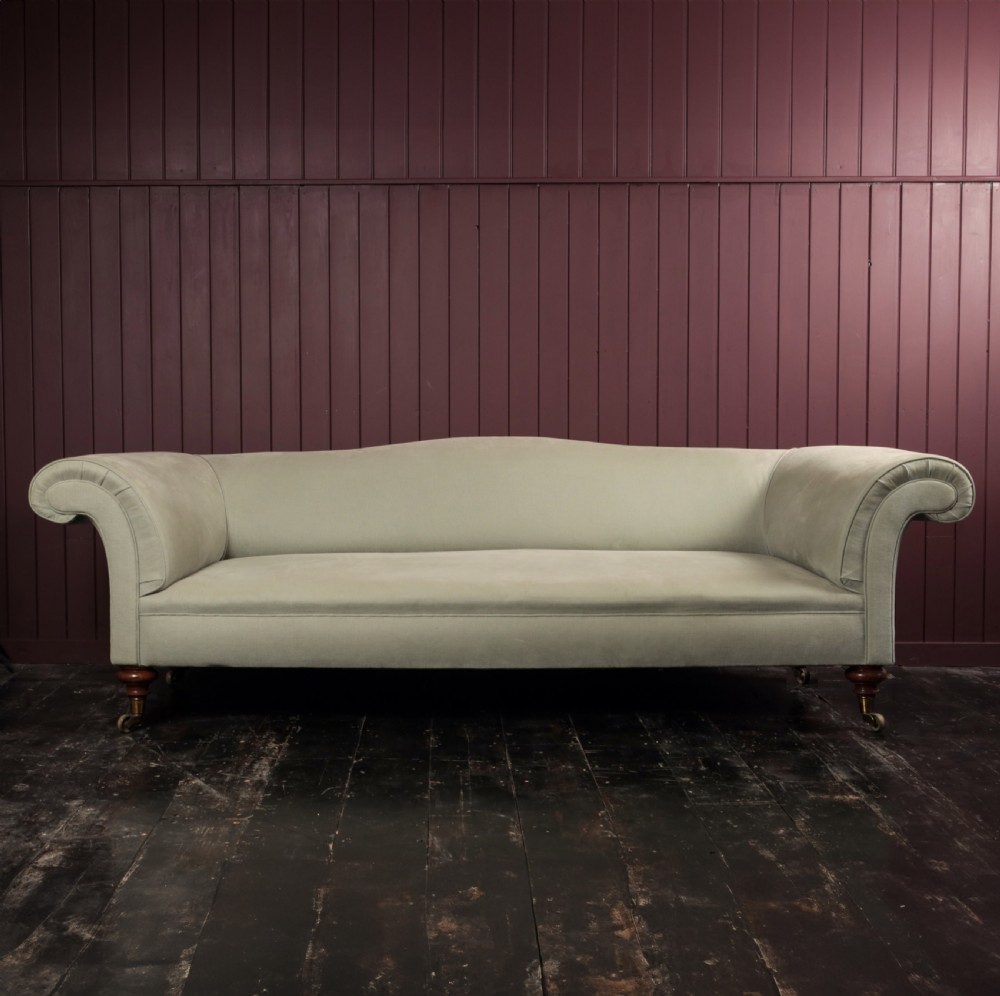 A nineteenth-century upholstered sofa featuring low scroll arms, a contoured backrest, and turned wooden legs on brass castors.