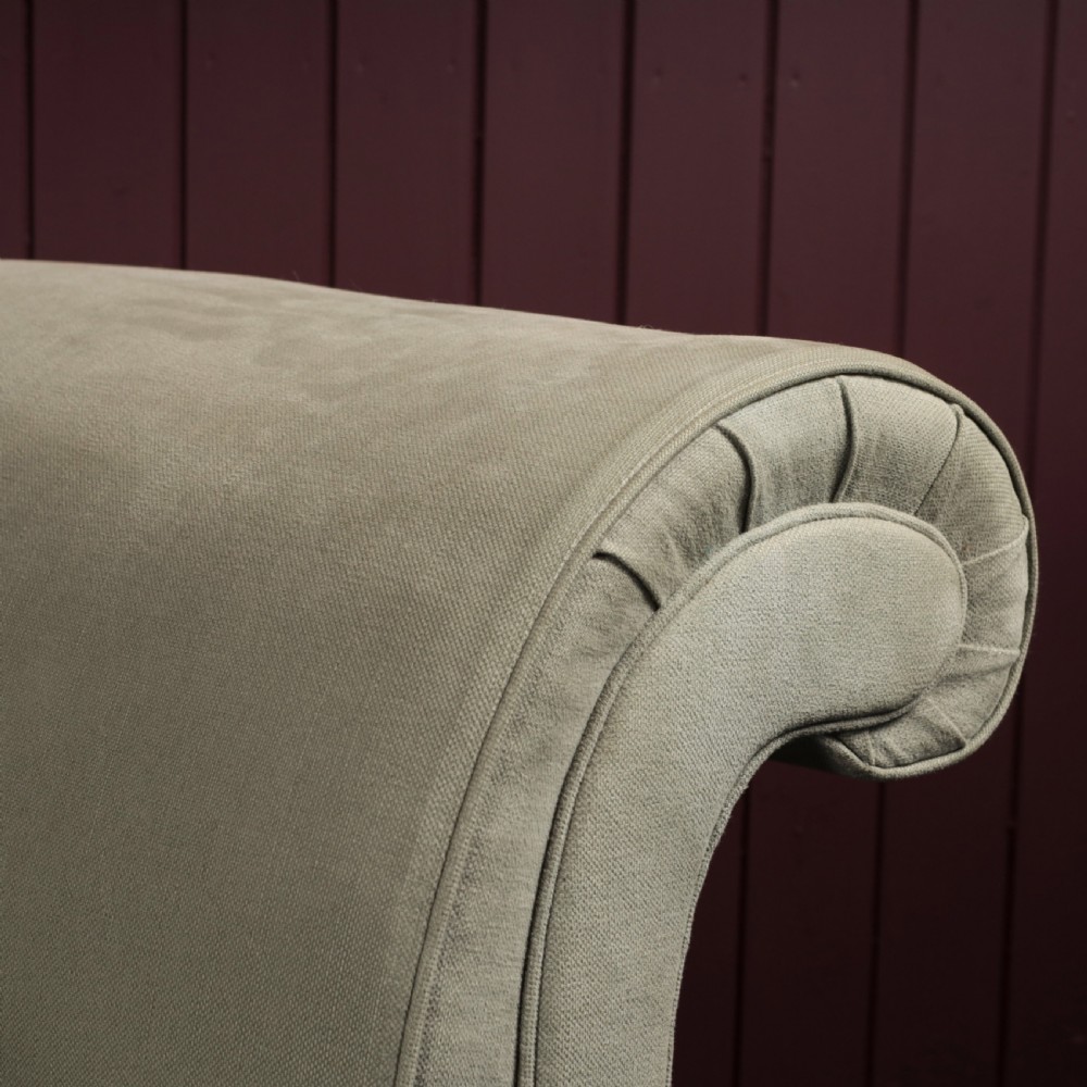 A nineteenth-century upholstered sofa featuring low scroll arms, a contoured backrest, and turned wooden legs on brass castors. View II