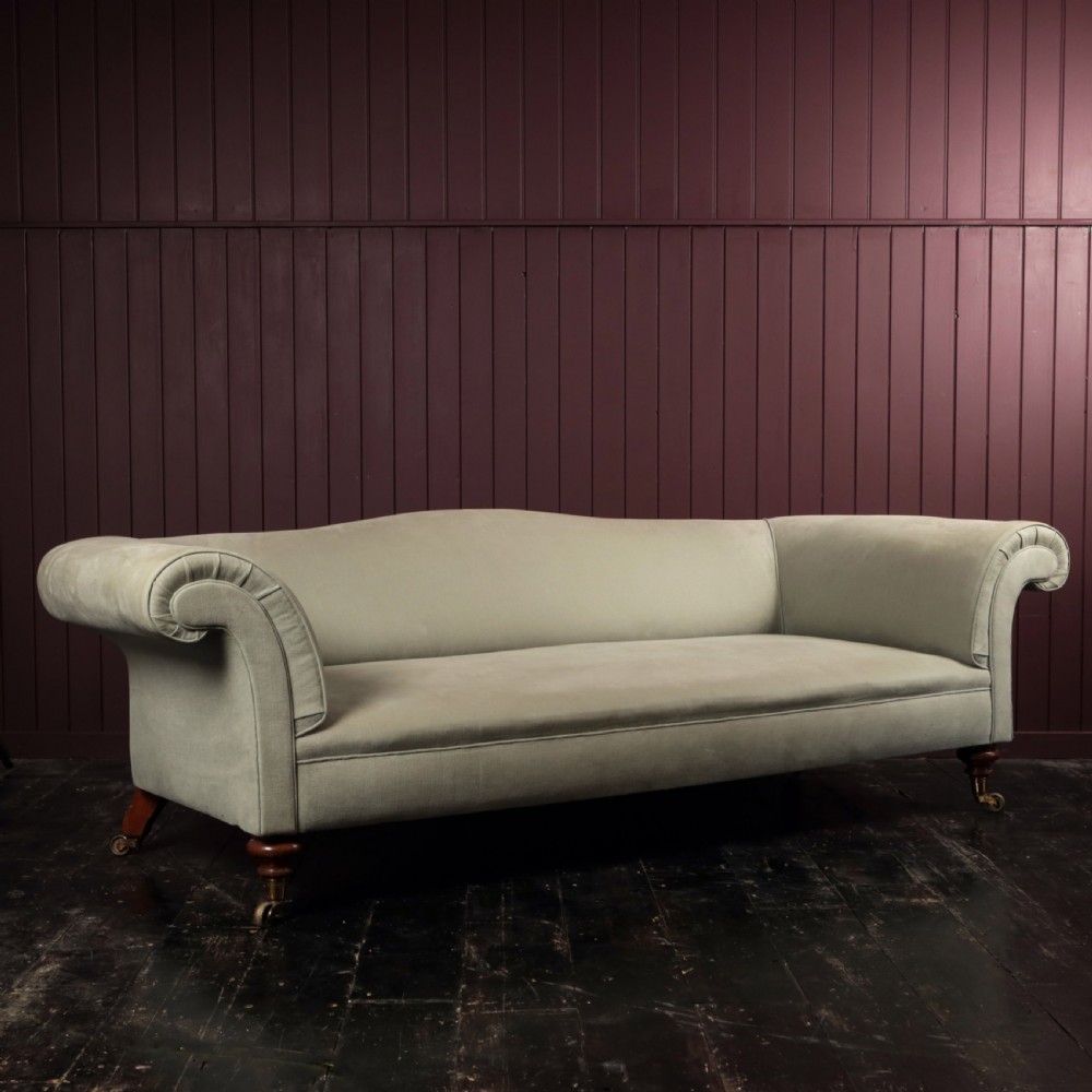 A nineteenth-century upholstered sofa featuring low scroll arms, a contoured backrest, and turned wooden legs on brass castors. View III
