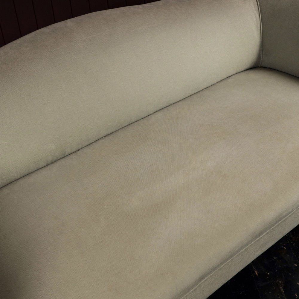 A nineteenth-century upholstered sofa featuring low scroll arms, a contoured backrest, and turned wooden legs on brass castors. View IV
