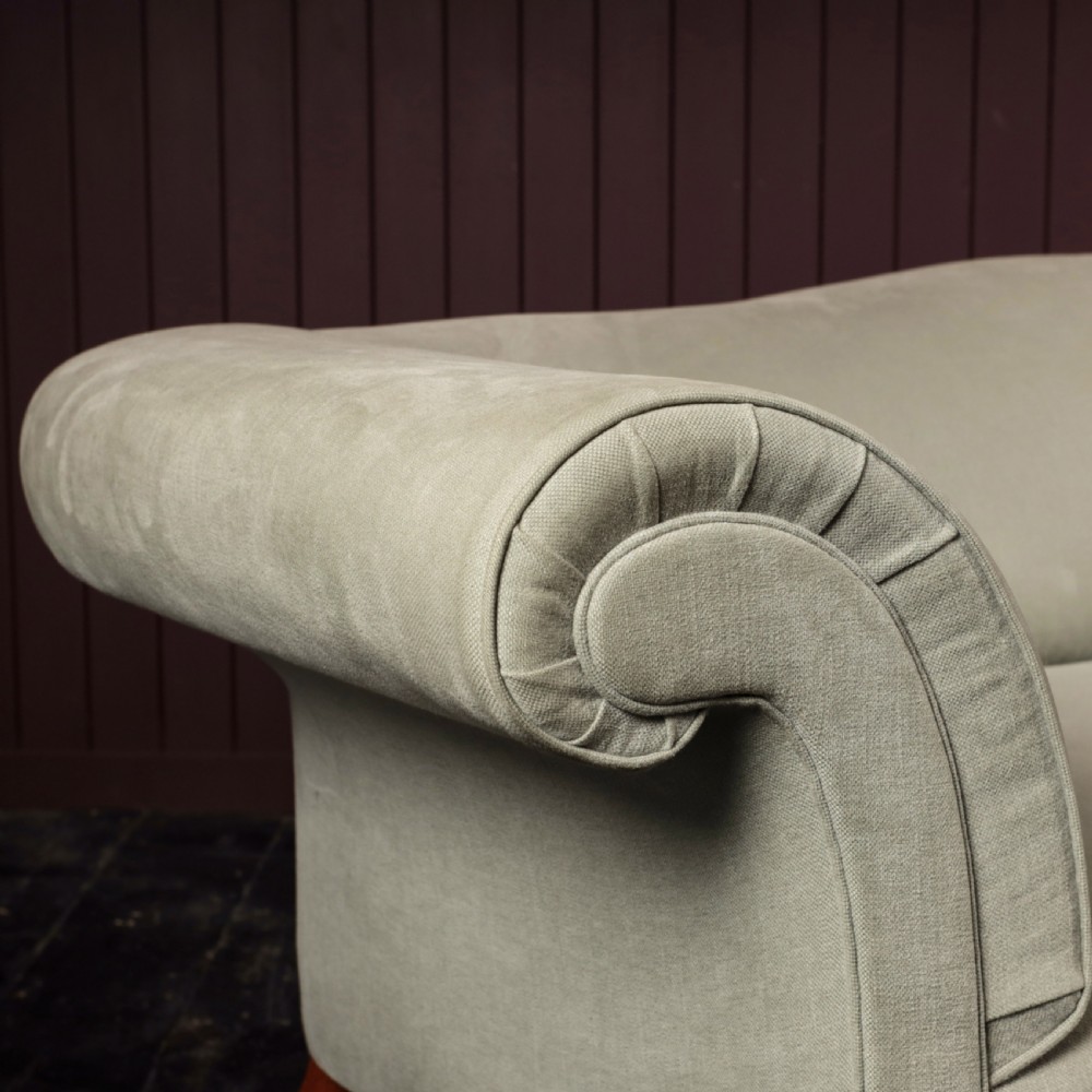 A nineteenth-century upholstered sofa featuring low scroll arms, a contoured backrest, and turned wooden legs on brass castors. View V