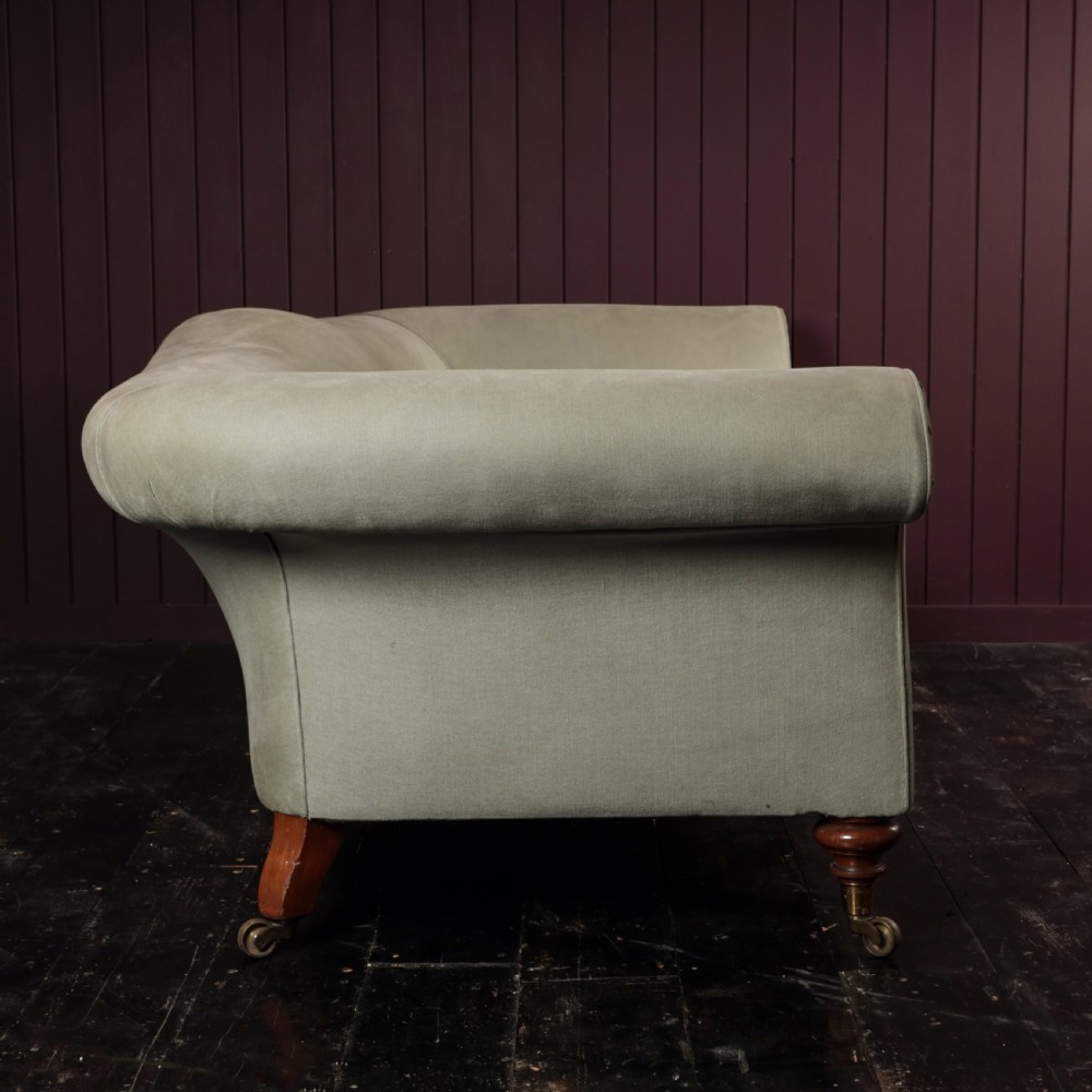 A nineteenth-century upholstered sofa featuring low scroll arms, a contoured backrest, and turned wooden legs on brass castors. View VII