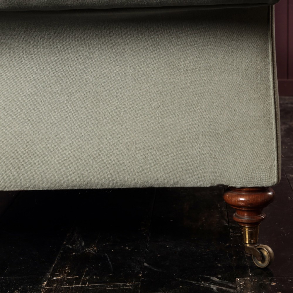 A nineteenth-century upholstered sofa featuring low scroll arms, a contoured backrest, and turned wooden legs on brass castors. View VIII