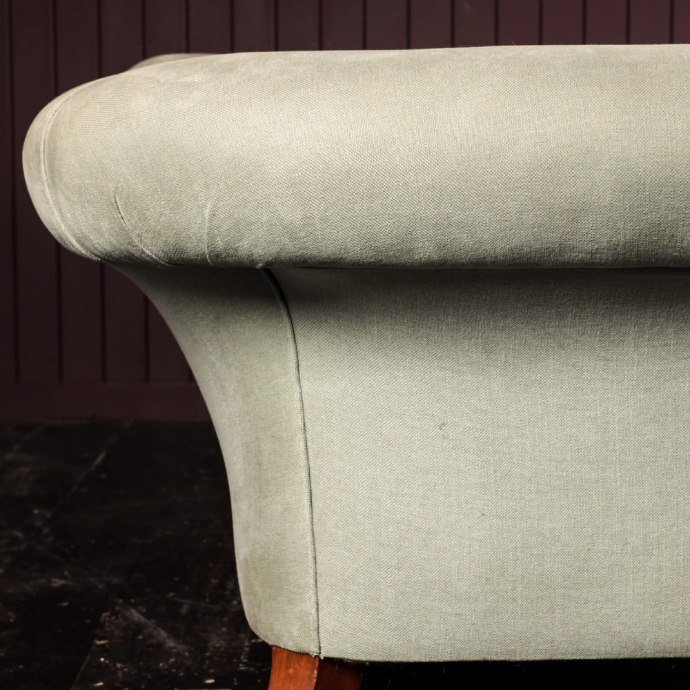 A nineteenth-century upholstered sofa featuring low scroll arms, a contoured backrest, and turned wooden legs on brass castors. View IX