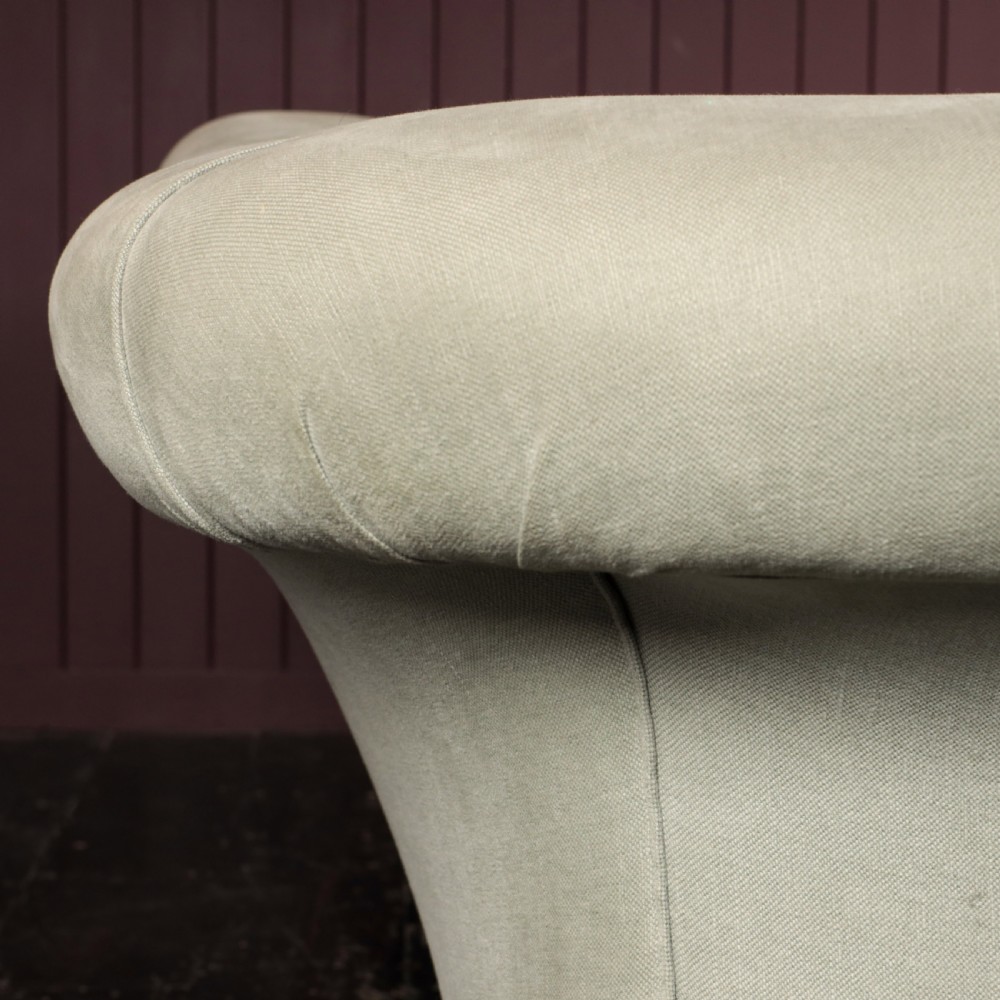 A nineteenth-century upholstered sofa featuring low scroll arms, a contoured backrest, and turned wooden legs on brass castors. View X