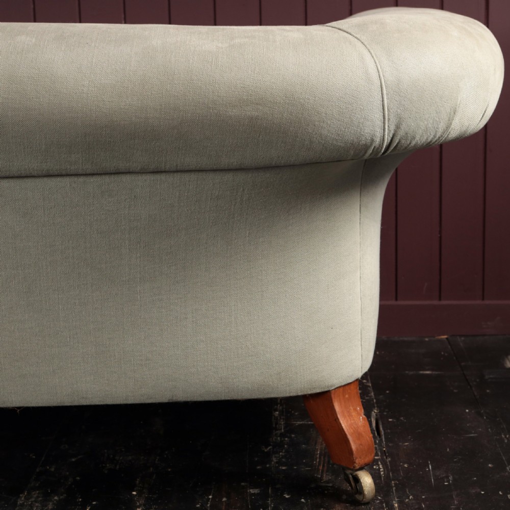 A nineteenth-century upholstered sofa featuring low scroll arms, a contoured backrest, and turned wooden legs on brass castors. View XI