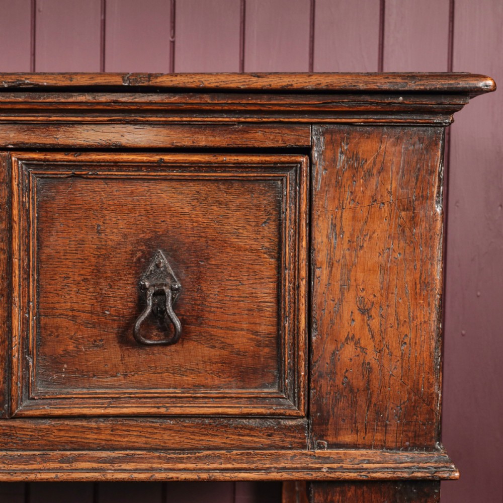 A long 17th-century dark oak dresser base featuring six geometric-moulded drawer fronts with iron teardrop handles and shaped legs. View V