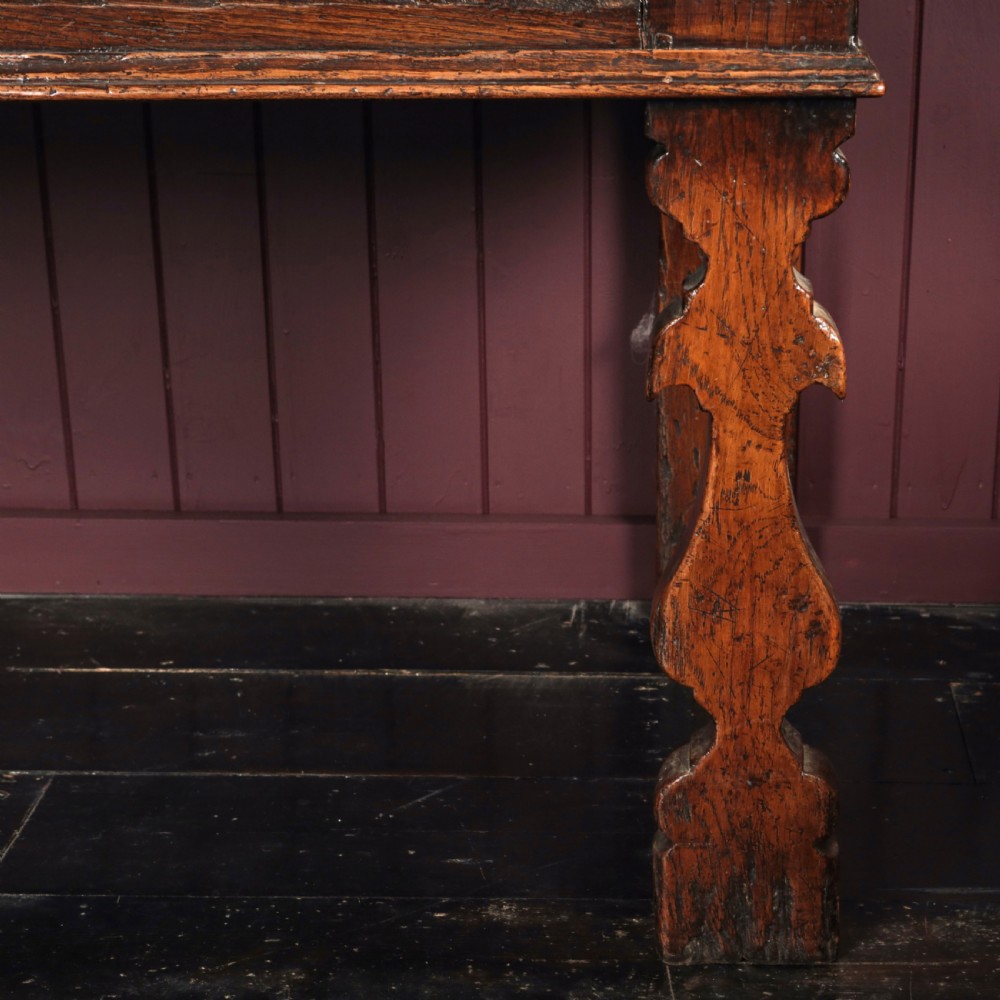 A long 17th-century dark oak dresser base featuring six geometric-moulded drawer fronts with iron teardrop handles and shaped legs. View VI