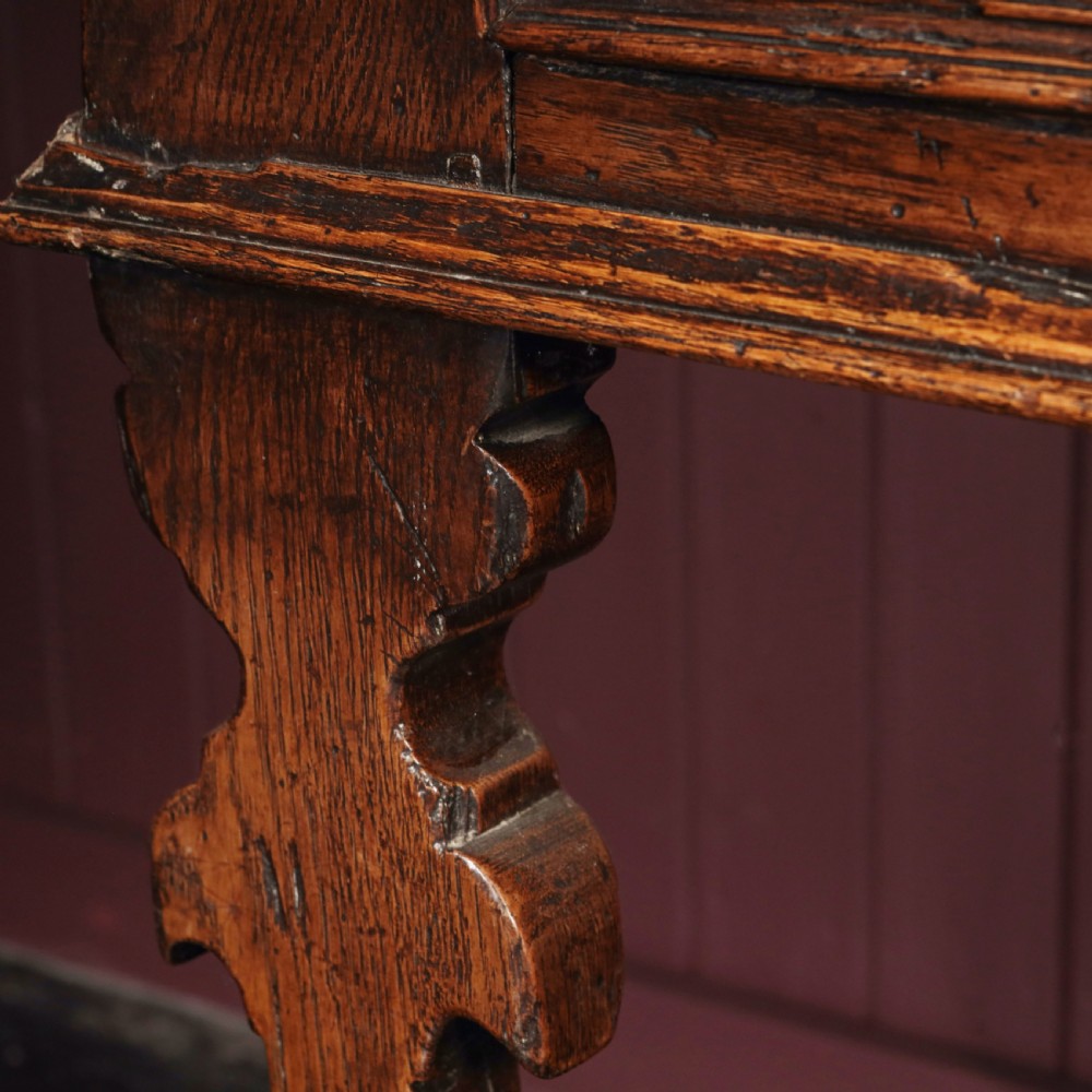 A long 17th-century dark oak dresser base featuring six geometric-moulded drawer fronts with iron teardrop handles and shaped legs. View IX