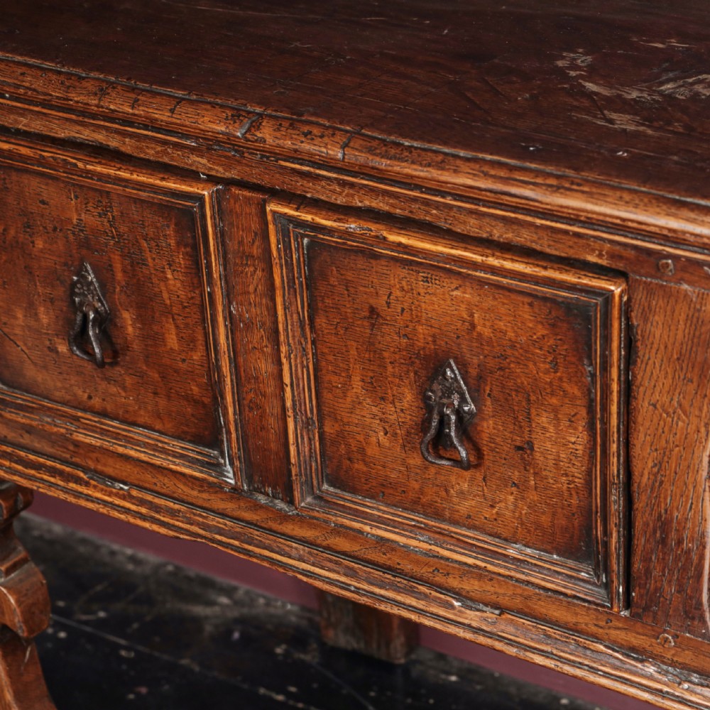 A long 17th-century dark oak dresser base featuring six geometric-moulded drawer fronts with iron teardrop handles and shaped legs. View X