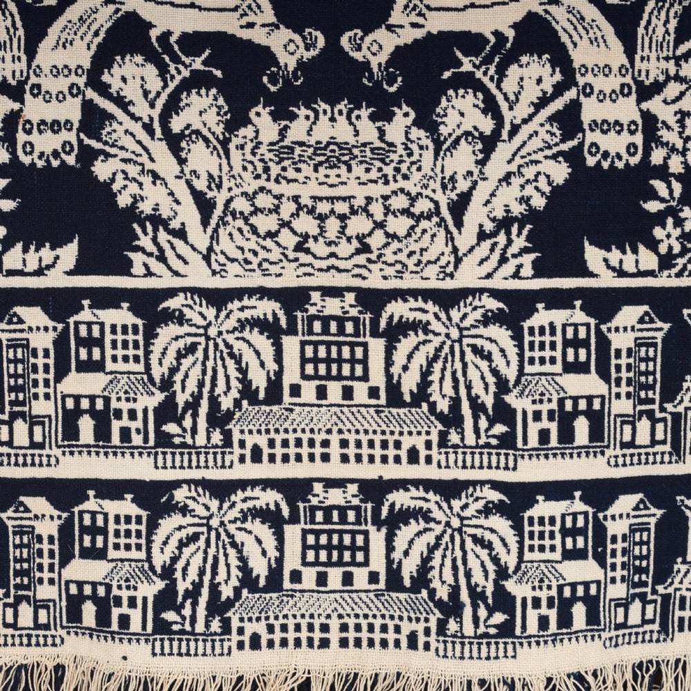 A nineteenth-century woven Jacquard coverlet in navy blue and cream featuring repeating floral urns, birds, and an architectural border with fringe. View III