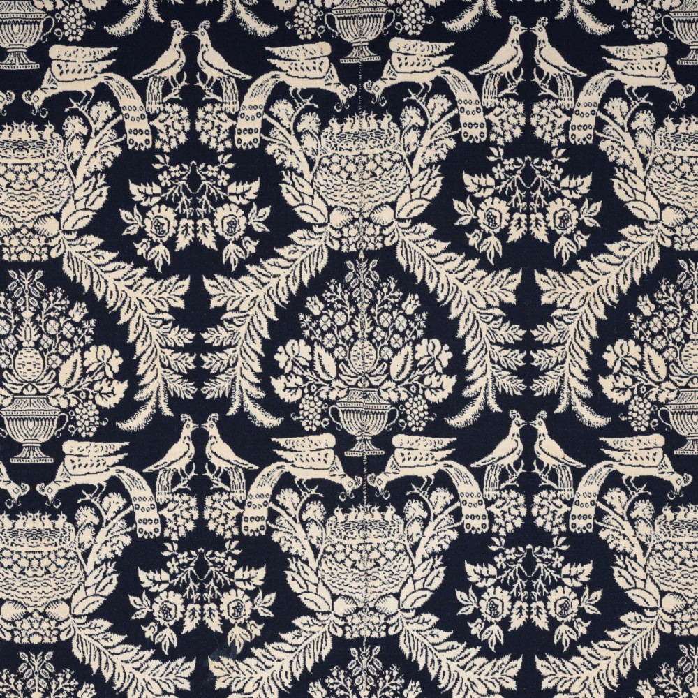 A nineteenth-century woven Jacquard coverlet in navy blue and cream featuring repeating floral urns, birds, and an architectural border with fringe. View IV