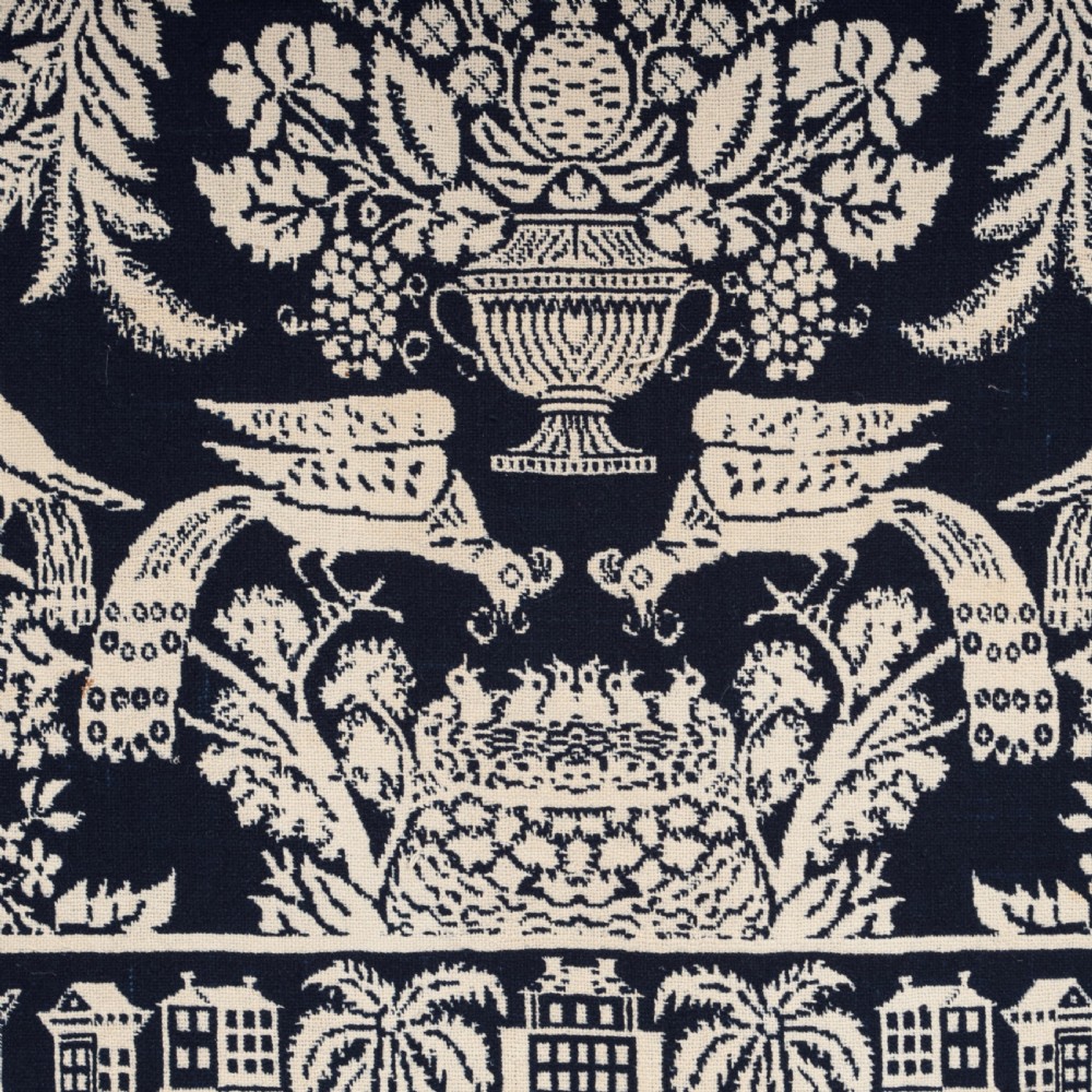 A nineteenth-century woven Jacquard coverlet in navy blue and cream featuring repeating floral urns, birds, and an architectural border with fringe. View VI
