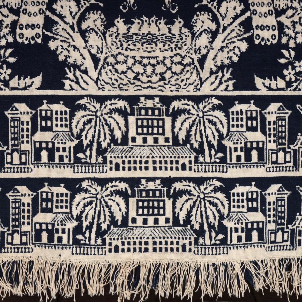 A nineteenth-century woven Jacquard coverlet in navy blue and cream featuring repeating floral urns, birds, and an architectural border with fringe. View XII