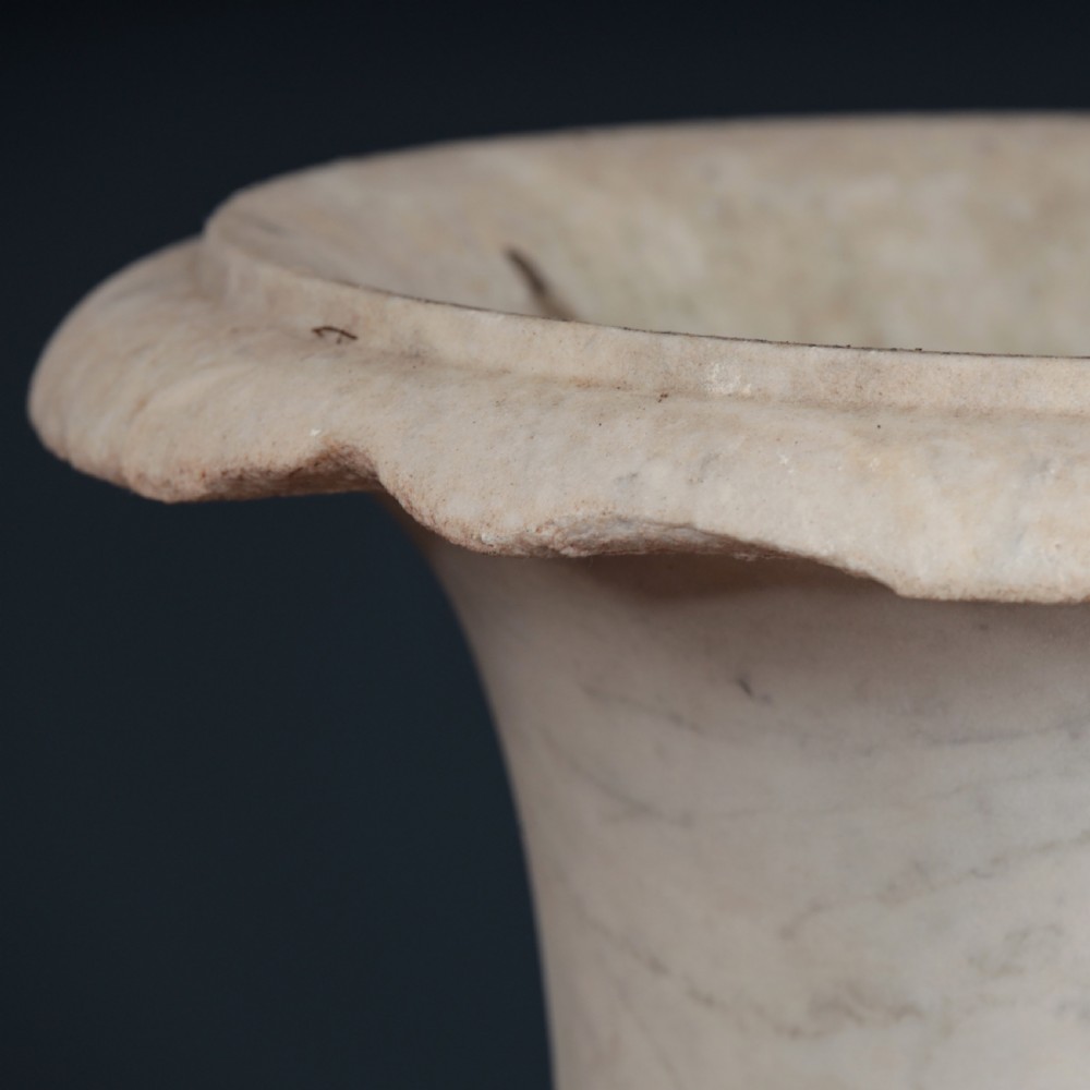 A pair of hand-carved white marble campana urns featuring gadrooned lower bodies and flared rims raised on square plinths. View II