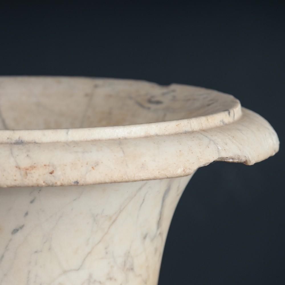 A pair of hand-carved white marble campana urns featuring gadrooned lower bodies and flared rims raised on square plinths. View III