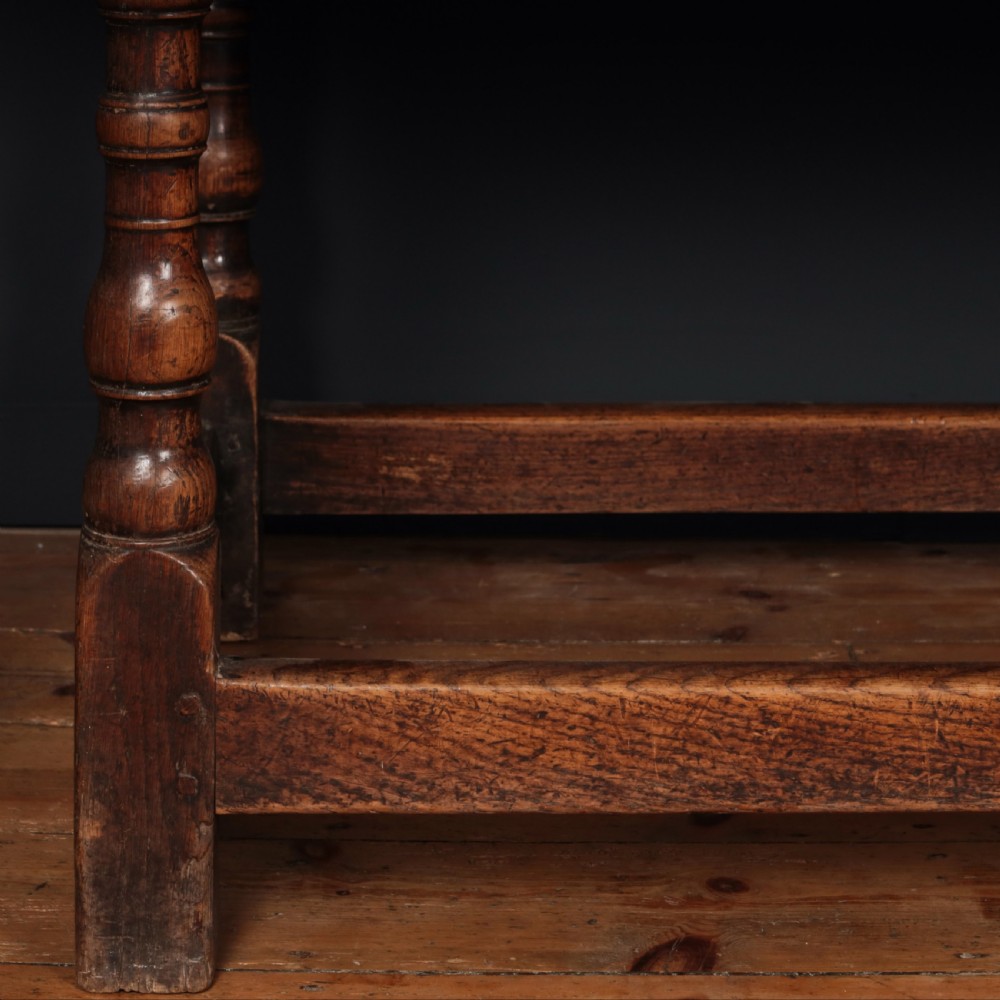 A long 17th-century oak refectory table featuring turned baluster legs, low stretchers, and a thick plank top. View III