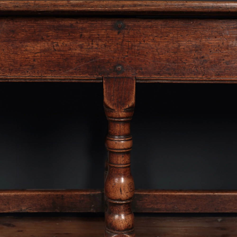 A long 17th-century oak refectory table featuring turned baluster legs, low stretchers, and a thick plank top. View IV