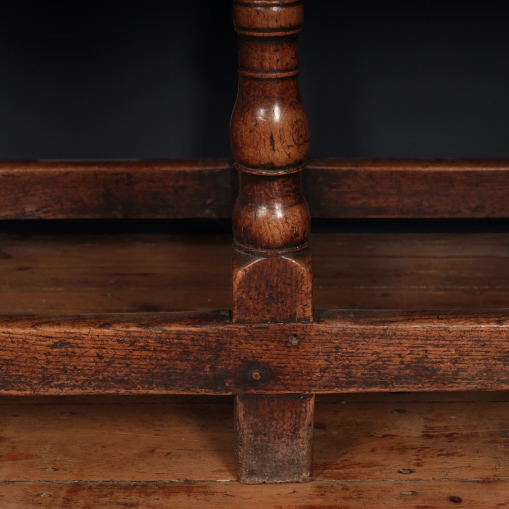 A long 17th-century oak refectory table featuring turned baluster legs, low stretchers, and a thick plank top. View V